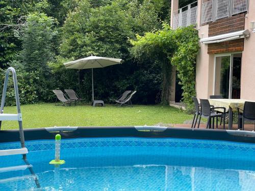 - une piscine avec un parasol, des chaises et une table dans l'établissement Indoor-Outdoor Villa with Panoramic Mountain Views Near Pyrenees Hikes & Atlantic Beaches, à Espoey