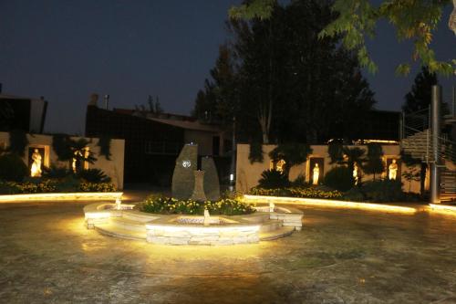 a fountain in a courtyard at night with lights at Layali Al Shams Hotel in ‘Anjar