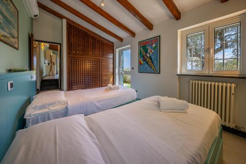 two beds in a room with two windows at LA CASA DI PIETRA Piscina e Panorama da Sogno in Santa Margherita Ligure