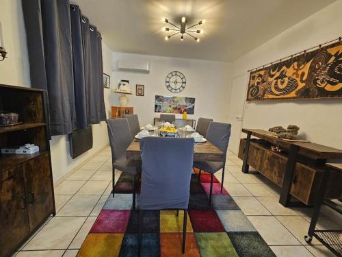 une salle à manger avec une table, des chaises et une horloge dans l'établissement La Casa D'Eole YourHostHelper, à Narbonne