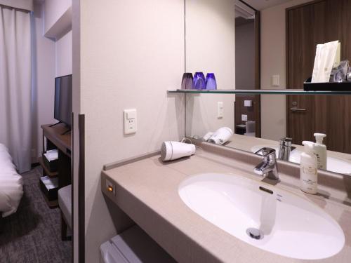 a bathroom with a sink and a large mirror at Dormy Inn Premium Shibuya-jingumae in Tokyo