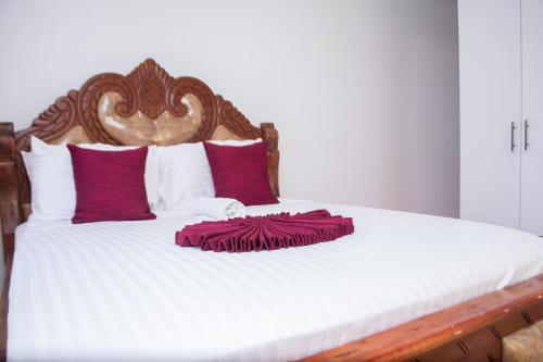 a bed with red and white pillows on it at Baali Diani Apartments in Ukunda