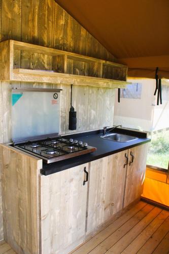 - une cuisine équipée d'une cuisinière et d'un évier dans une remorque dans l'établissement Les lodges de Baca, à Le Voide