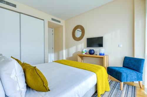 a bedroom with a bed and a blue chair at Praia do Sal Resort in Alcochete
