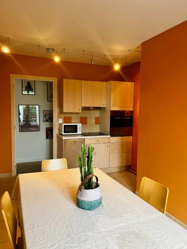 - une cuisine avec une table et une plante en pot dans l'établissement Le Clairmont, à Bagnoles-de-l'Orne