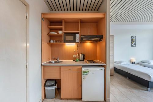 a kitchen with a sink and a microwave and a bed at Condo Gardens Brussels in Brussels