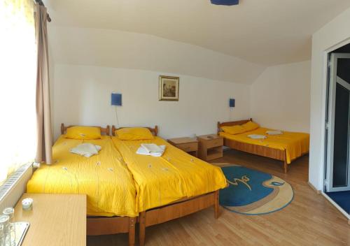 a bedroom with two beds with yellow sheets at Pensiunea Hyperion Cormaia in Sîngeorz-Băi