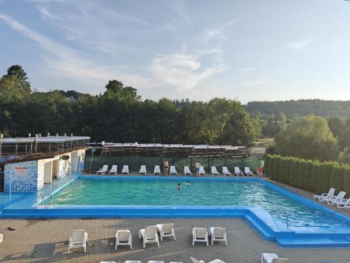 a swimming pool with chairs and people in the water at Pensiunea Hyperion Cormaia in Sîngeorz-Băi