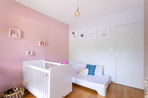 - un lit bébé blanc dans une chambre blanche dotée d'un canapé dans l'établissement Piscine, Clim, BBQ et transat, à Villevieille