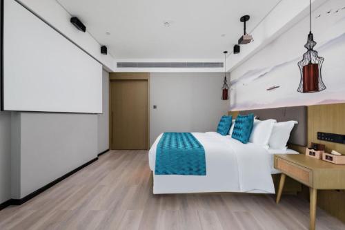 a bedroom with a white bed and a table at Mehood Lestie, Nanning East Railway Station in Nanning