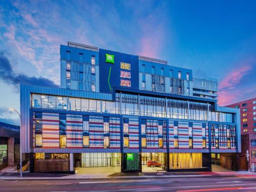 a blue building with many windows on a street at Ibis Styles Hobart in Hobart