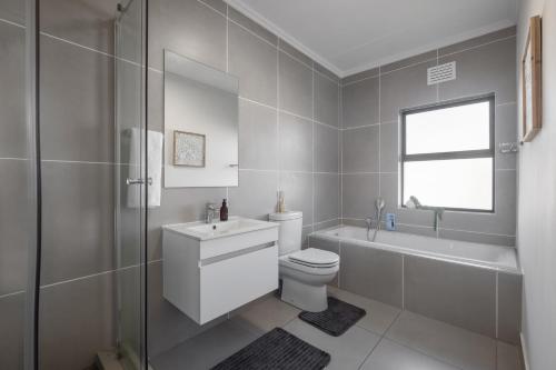 a bathroom with a toilet and a sink and a bath tub at Ballito Village Luxury Apartments in Ballito