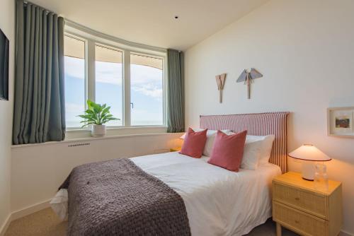a bedroom with a bed with red pillows and a window at The View at Shoreline by Bloom Stays in Folkestone