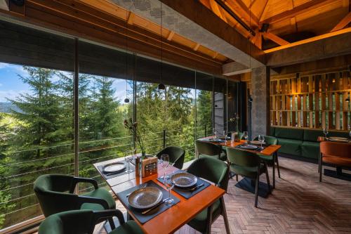 a restaurant with tables and chairs and large windows at Stara Pravda Hotel in Bukovel