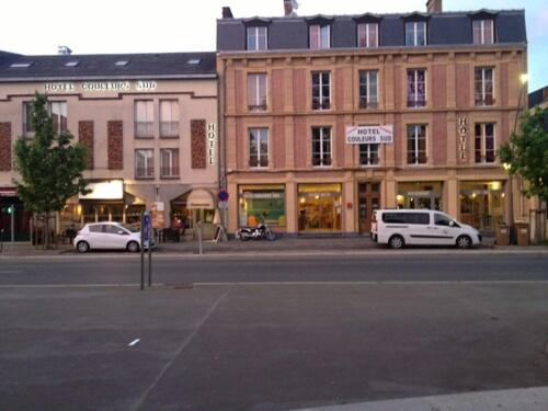 a street with two cars parked in front of a building at Hotel Couleurs Sud Centre-ville Gare Charleville-Mézières in Charleville-Mézières