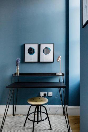 a blue wall with a table and a stool in a room at Incredible contemporary flat in heart of west end in Glasgow