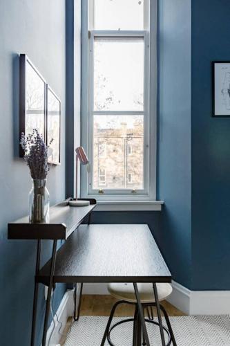 a blue room with a desk and a window at Incredible contemporary flat in heart of west end in Glasgow