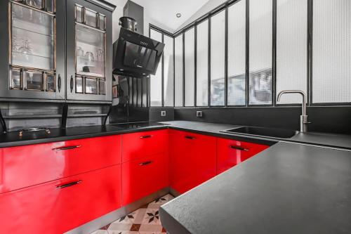 une cuisine avec des armoires rouges et un évier dans l'établissement Le Finhley - 5p - Proche Disney & Paris, à Le Raincy