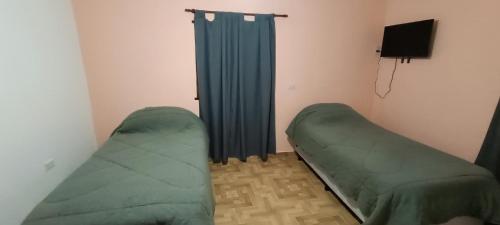 a room with two green beds and a curtain at Apartamiento temporario Catamarca in San Fernando del Valle de Catamarca