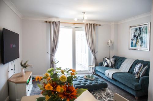 a living room with a blue couch and a table at Stylish quaint home hosted by ESONGRACE Stays in Stoke-on-Trent - Perfect for Families - Contractors - Holiday makers - Emergency Housing - Professionals in Stoke on Trent