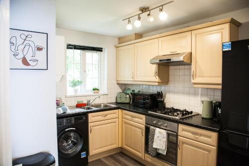 a kitchen with wooden cabinets and a washer and dryer at Stylish quaint home hosted by ESONGRACE Stays in Stoke-on-Trent - Perfect for Families - Contractors - Holiday makers - Emergency Housing - Professionals in Stoke on Trent