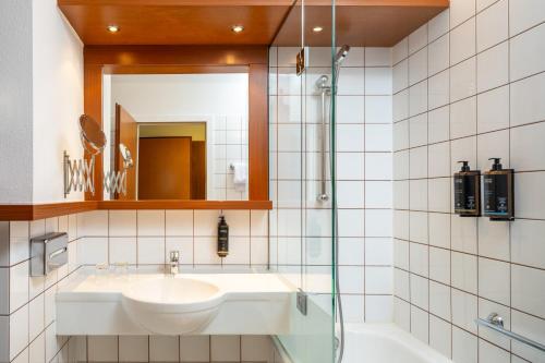 a bathroom with a sink and a mirror and a tub at Hotel Mercure Wien Westbahnhof in Vienna