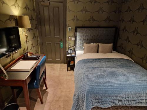 a bedroom with a bed and a desk and a computer at The City of London Club in London