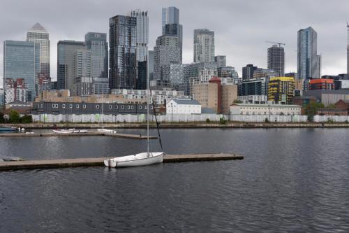a sailboat on a dock in the water with a city at Charming and Cosy Canary Wharf Room with Stunning Views in London