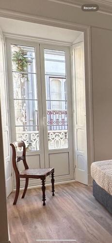a bedroom with a chair and a door with a window at Azor International Hostel in Ponta Delgada