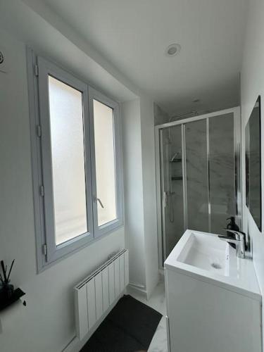 une salle de bain blanche avec un lavabo et une douche dans l'établissement 2 Pièces Parisien à Proximité de la Défense, à Puteaux