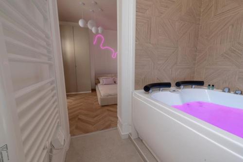 a bathroom with a bath tub with pink paint on the wall at L Envolé - Jacuzzi - Proche Gare et Centre ville in Châlons-en-Champagne
