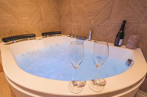 two wine glasses sitting in a tub with wine bottles at L Envolé - Jacuzzi - Proche Gare et Centre ville in Châlons-en-Champagne