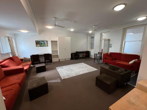 a living room with red couches and a piano at Wallaby Backpackers Hostel Perth - note - Valid passport required to check in - in Perth