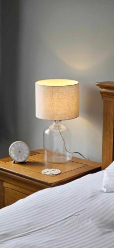 a lamp on a wooden table next to a bed at Halmer Grange Guest House in Goathland