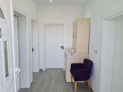 a hallway with a purple chair and a door at VIla Markel in Sarandë