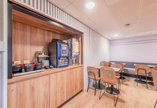 une salle à manger avec une table, des chaises et une télévision dans l'établissement B&B HOTEL Mulhouse Kingersheim, à Kingersheim