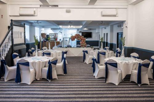 a banquet hall with white tables and chairs at The Imperial Crown Hotel in Halifax