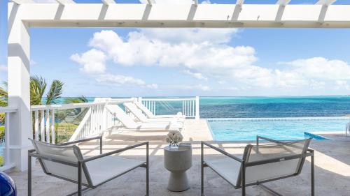 a patio with chairs and a view of the ocean at Reef Tides Luxury Beach House in Providenciales