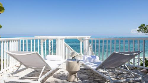 two chairs and a table on a balcony overlooking the ocean at Reef Tides Luxury Beach House in Providenciales
