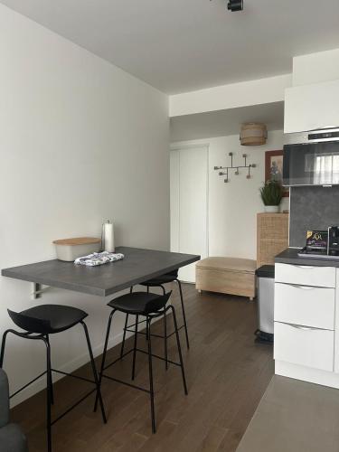 une cuisine avec une table et des tabourets dans une pièce dans l'établissement Charment F2 à 5 min de la Défense, à Puteaux