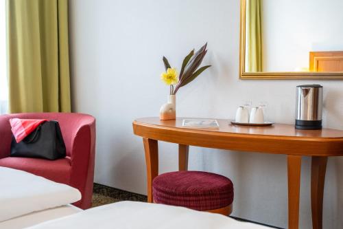 a room with a table and a chair and a mirror at Hotel Mercure Wien Westbahnhof in Vienna