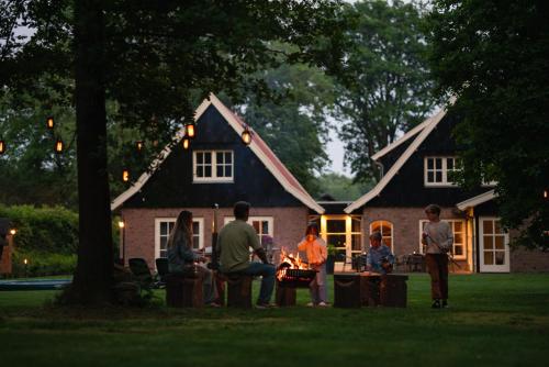 a group of people sitting around a fire in front of a house at 't Borghuis in Losser