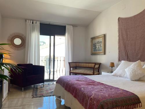 a bedroom with a bed and a chair and a window at Hostal de la Plaça - Hotel Boutique in Cabrils