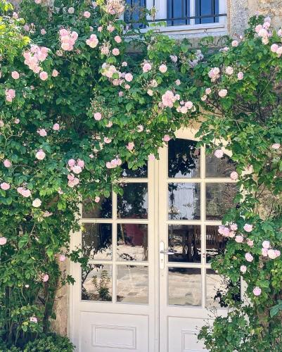 a white door with pink roses growing around it at Maison de vacances avec piscine chauffée, jacuzzi et jardin privé - proche circuit des 24h du Mans in Saint-Christophe-en-Champagne