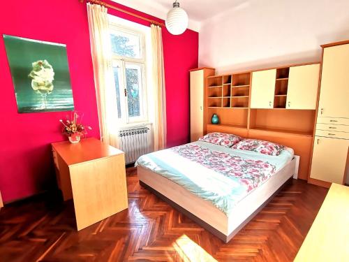 a bedroom with red walls and a bed and a window at Apartman Villa Adelina in Lovran