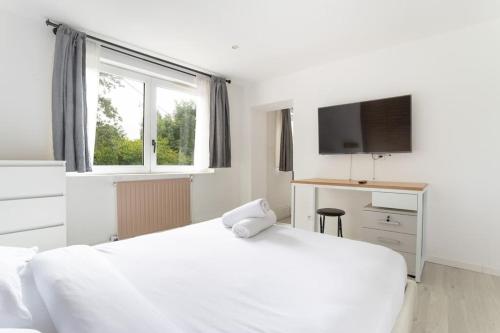 - une chambre avec un lit blanc, un bureau et une télévision dans l'établissement L'Urban chic - proche des transports, à Villeneuve d'Ascq