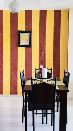 a dining room table with chairs and a striped wall at Appartement chic dans un complexe sécurisé à Malabata in Tangier