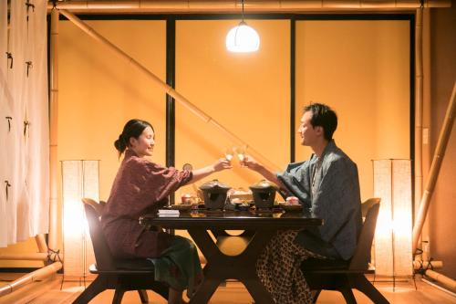a man and woman sitting at a table with candles at Izu atagawa Yubana mankai -Adult Only- in Higashiizu