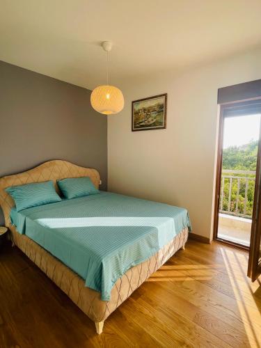 a bedroom with a bed with blue pillows and a window at Lavander Apartment W Pool and Private Beach in Tivat