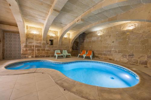 an indoor swimming pool in a building with a stone wall at Room 3 - family room x 3 by Solea in Għarb